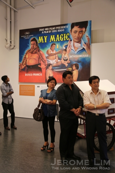 Former movie poster painter Mr Ang Hao Sai. Behind him is a hand-painted movie poster made for his 2008 film, My Magic.